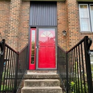 Red entry door with white trim on a brick home