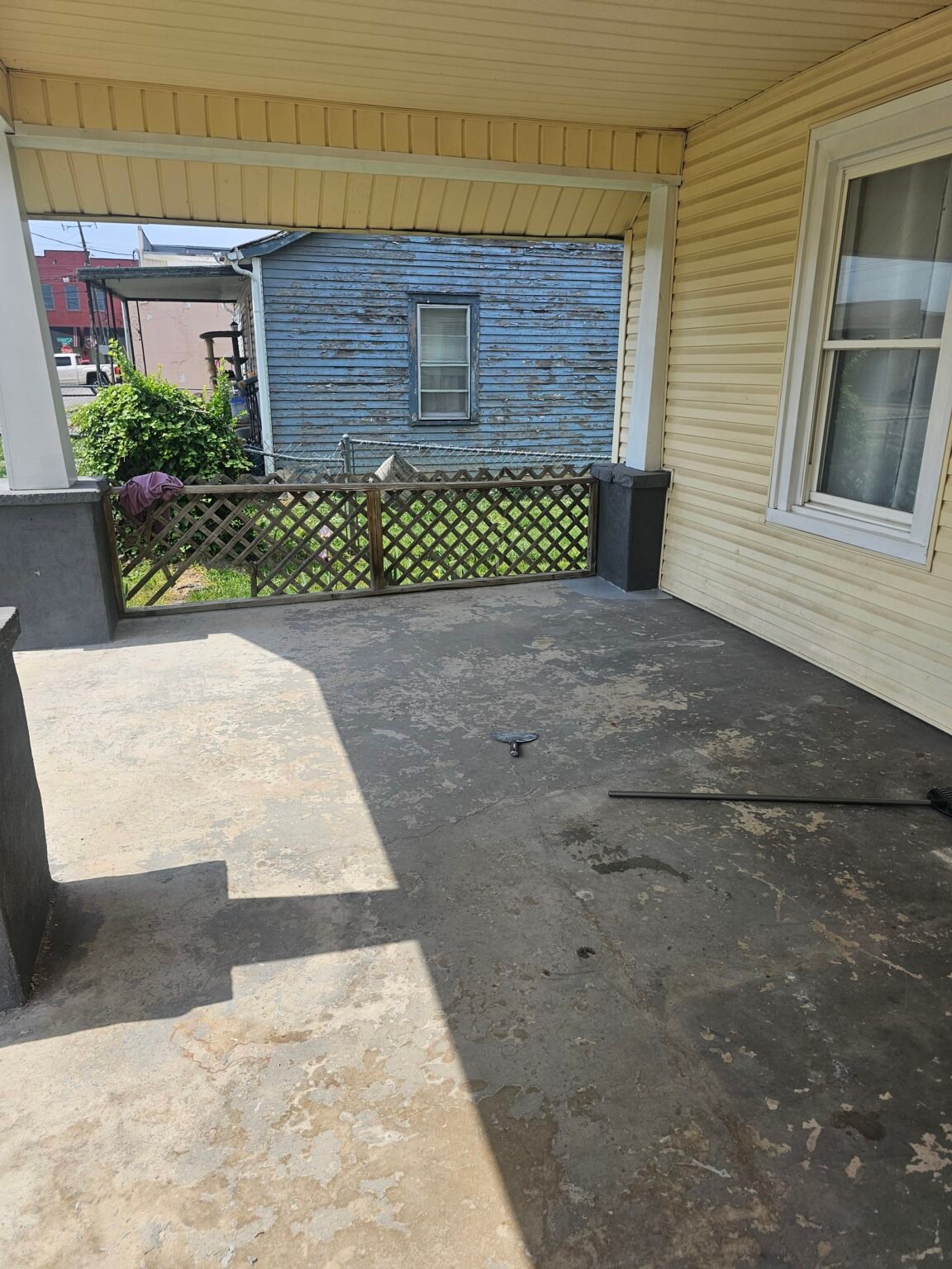 Covered porch floor before recoating, showing worn and flaking gray coating