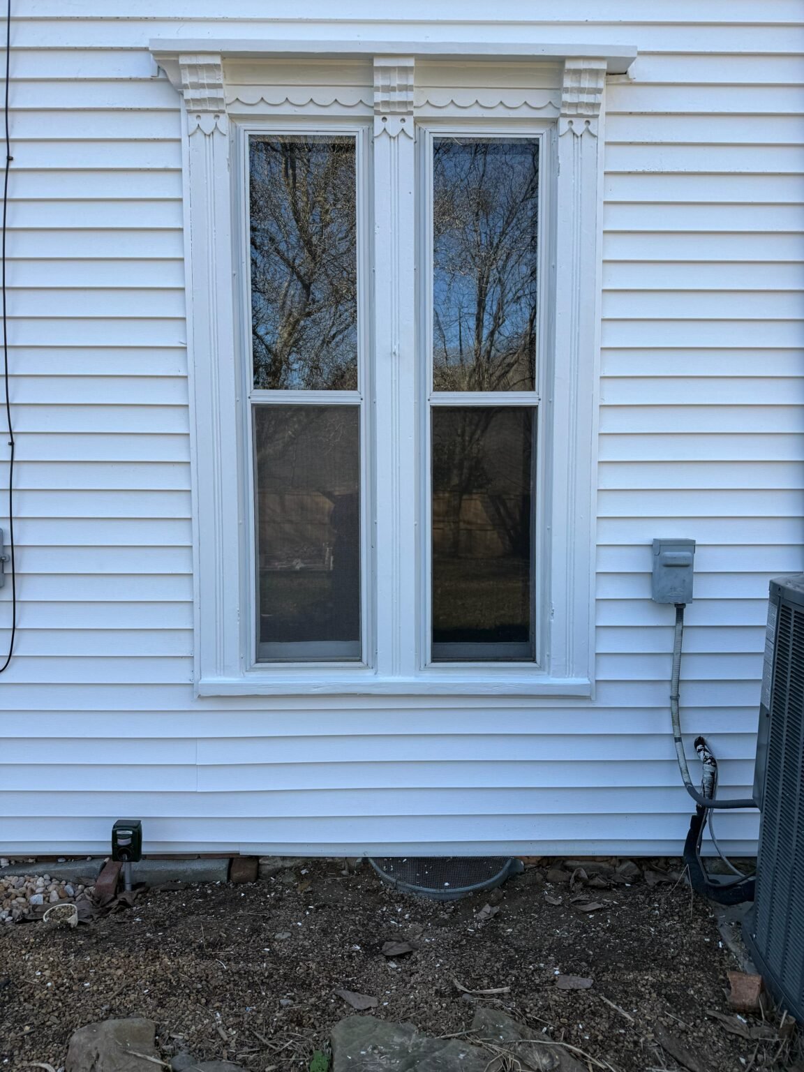 Decorative exterior window trim finished in white against white horizontal siding
