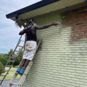 Painter working on brick beneath exterior roof trim