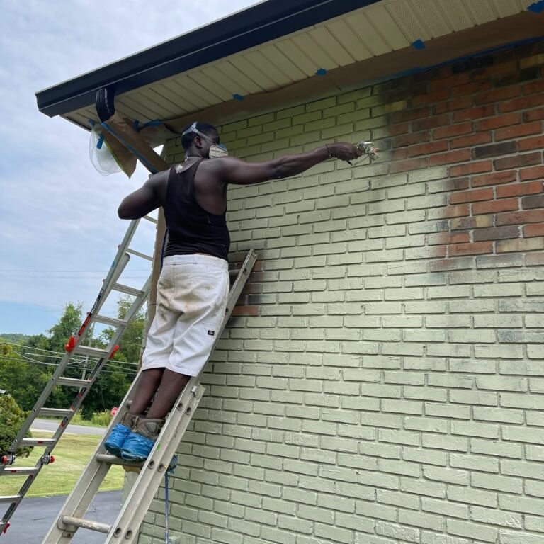 Painter working on a brick house exterior